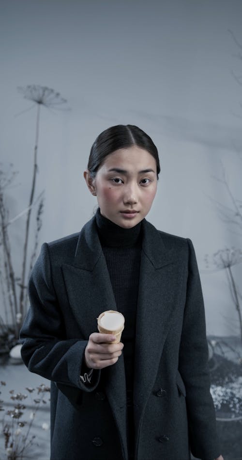 A Woman Eating Ice Cream while Looking at the Camera