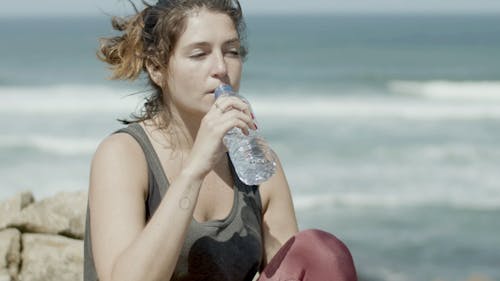 A Woman in Activewear Drinking Bottled Water