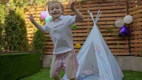 A Footage of a Little Boy Jumping on a Grass