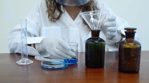 A Scientist Inserting a Funnel into a Glass Jar