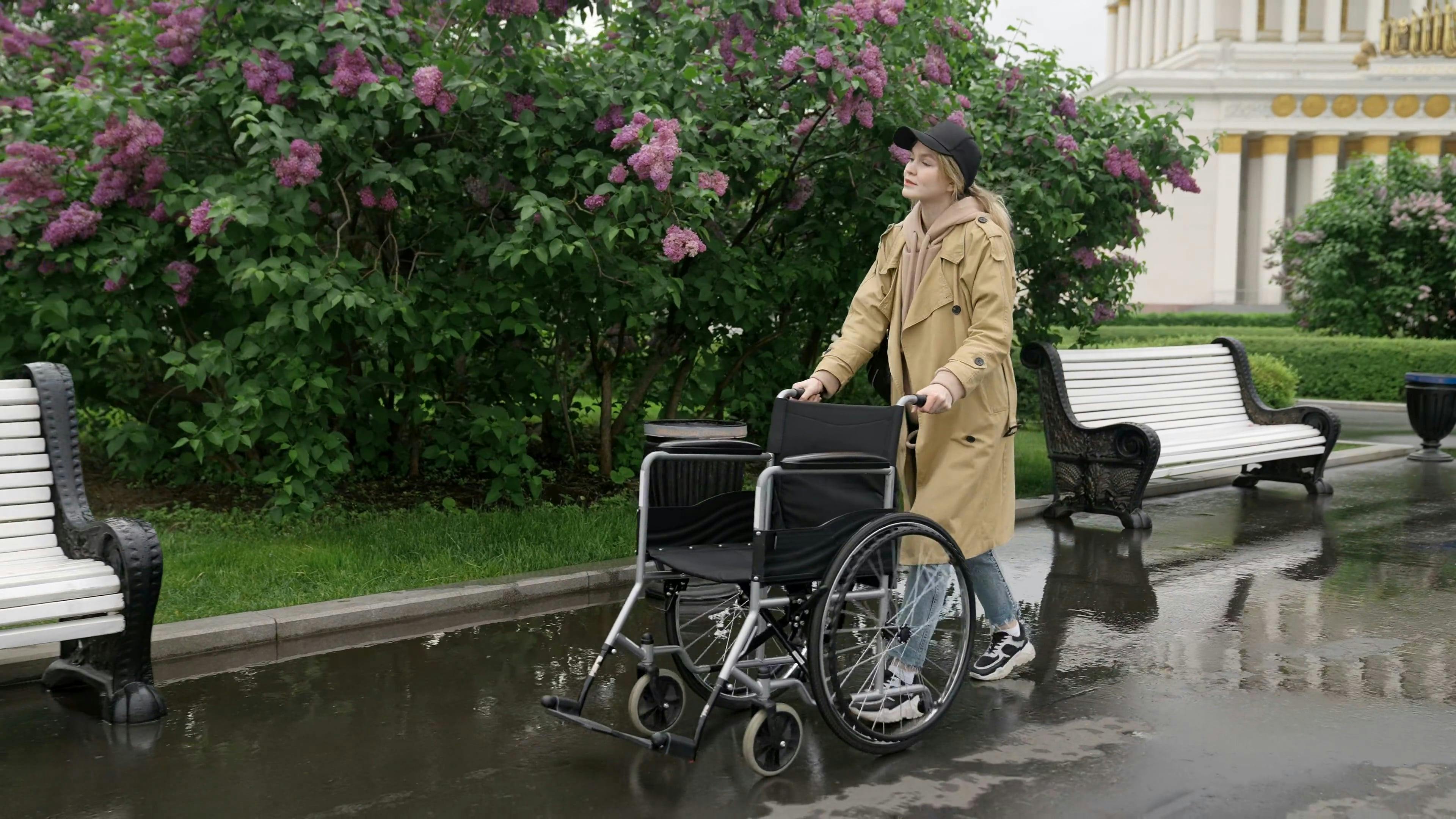 A Woman Pushing a Wheelchair while Walking · Free Stock Video