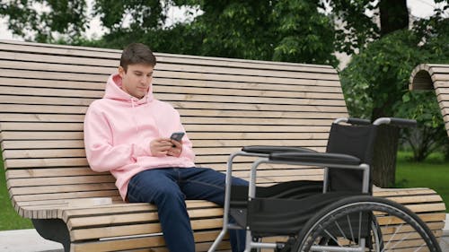 Man Sitting on a Bench While Using a Cellphone