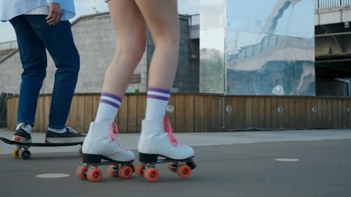 A Roller Skater And Skateboarder Rolling In The Street