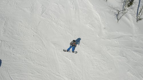 Drone Footage of a Person Snowboarding Downhill