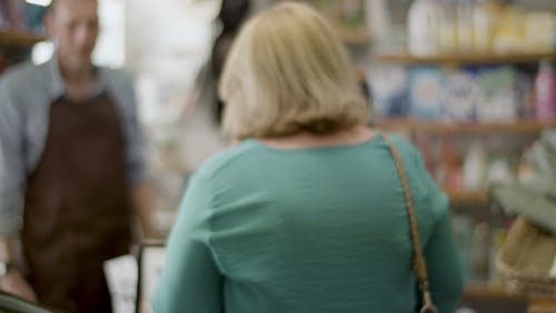 An Elderly Woman Walking to a Store Cashier