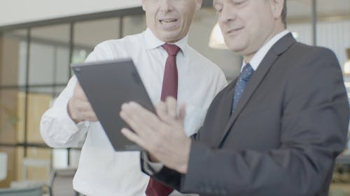 Businessmen Looking at a Tablet Then Doing a Handshake