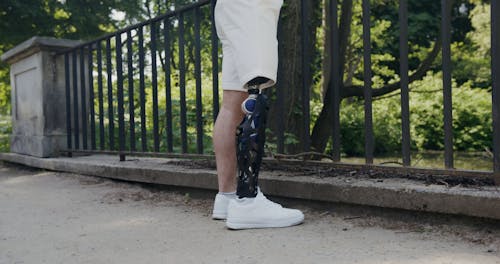 A Man with a Prosthetic Leg Walking on a Sidewalk