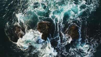 aerial view of a waves crashing on rocks