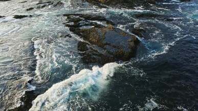 aerial view of a waves crashing on rocks