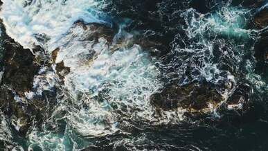 aerial view of a waves crashing on rocks