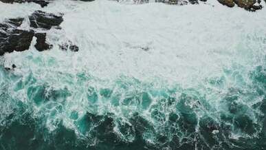 aerial view of a waves crashing on rocks