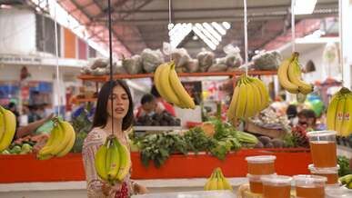 woman looking at hanging bananas