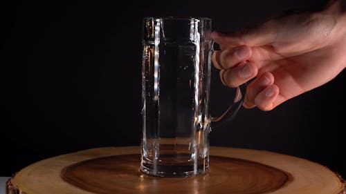 A Person Pouring a Beer into a Mug Glass