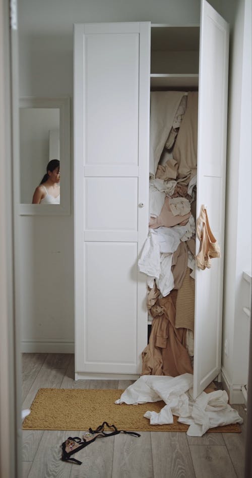 Woman Putting Back Her Clothes on the Cabinet 