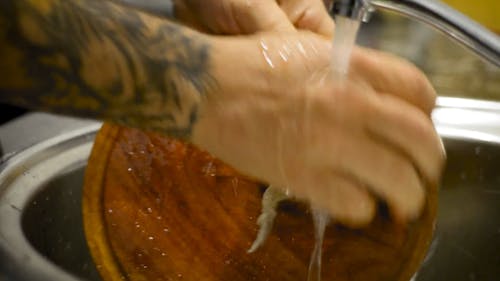 A Person Washing a Wooden Plate 