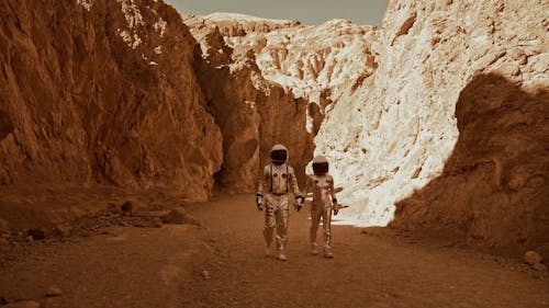 An Astronaut Couple Holding Hands while Walking