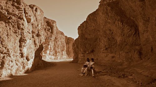 An Astronaut Couple Sitting on Rocks