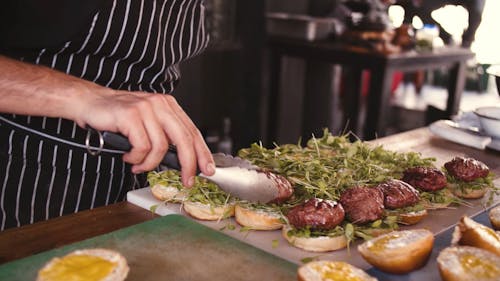 A Person Preparing a Grilled Hamburger