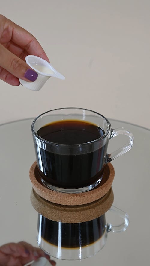 Person Pouring Milk in a Cup of Coffee