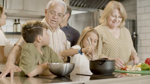 An Elderly Couple Cooking with Grandchildren