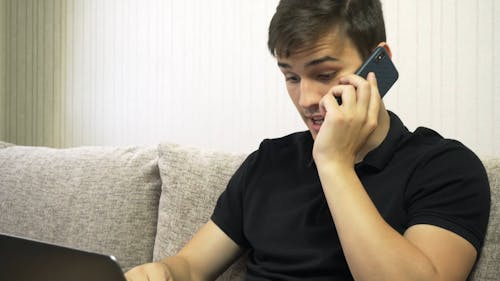 Man Talking on the Phone While Using Laptop