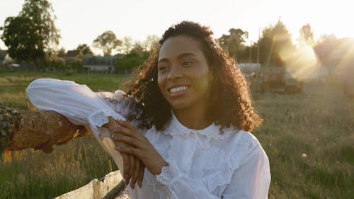 A Woman Posing while Leaning on a Wooden Fence 