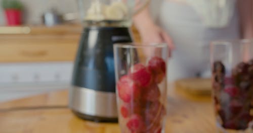 A Woman Placing Strawberries in a Blender