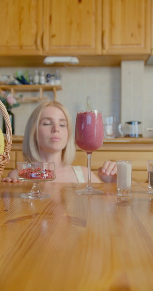 A Woman Sprinkling an Ingredient on her Fruit Shake