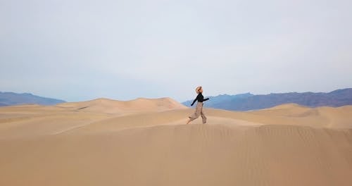 Drone Footage of a Woman Running on Dunes