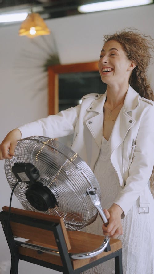 A Woman Standing in Front of the Electric Fan