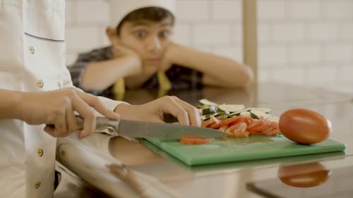 A Boy Looking at a Chef Cutting Tomatoes