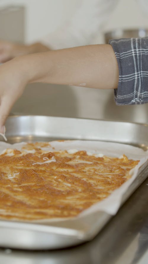 Close up of a Person Sprinkling Cheese on Pizza Dough