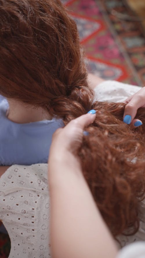 Close up of a Person Braiding a Woman's Hair