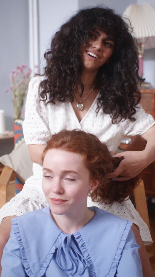 A Woman Braiding her Friend's Hair