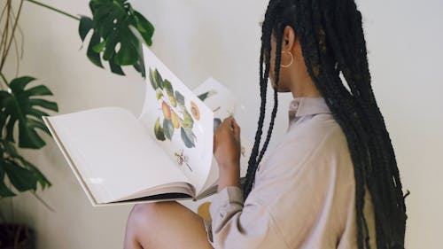 A Woman Looking at Illustrations of Fruits in a Book