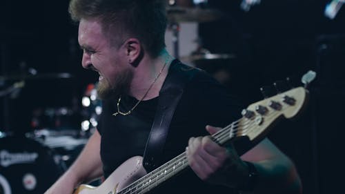 A Man Kneeling while Playing a Bass Guitar Onstage