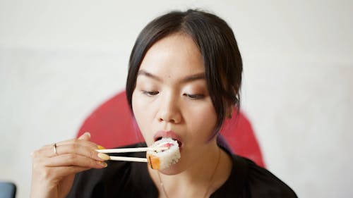 A Medium Close up of a Woman Eating a Sushi Roll