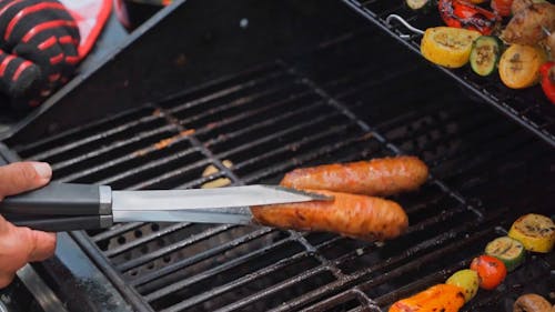 A Person Grilling Sausages