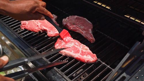 A Person Grilling Beef Steaks