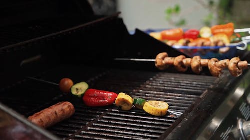 A Person Grilling Food on Skewers