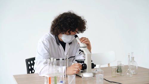 A Scientist Observing A Specimen Under A Microscope