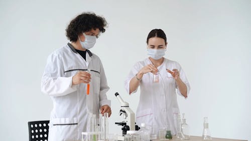 Scientists Mixing and Pouring Chemical in a Test Tube