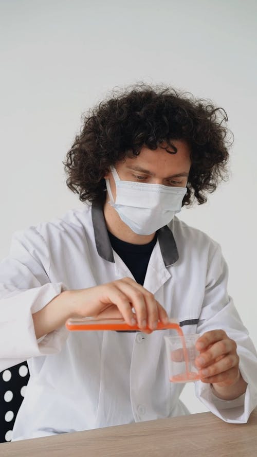 Chemist Pouring and Stirring Chemical in a Flask