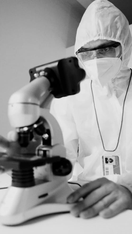 A Scientist using a Microscope in Full PPE