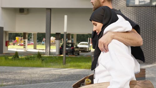 A Couple Walking while Holding Skateboards