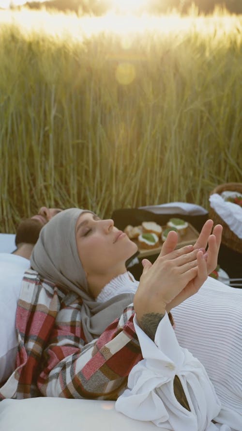A Couple Touching Hands while Lying Down at a Picnic