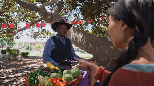 A Man Placing Vegetables in a Brown Paper Bag