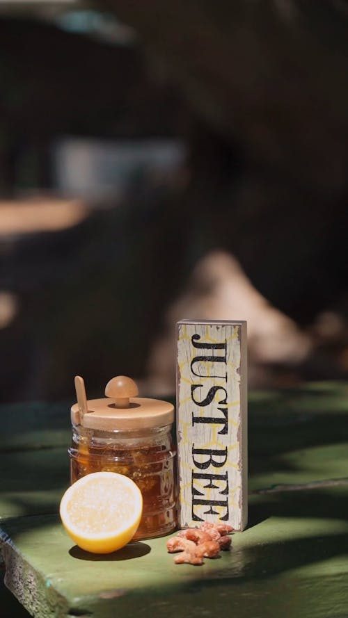 A Jar of Honey beside a Lemon Half