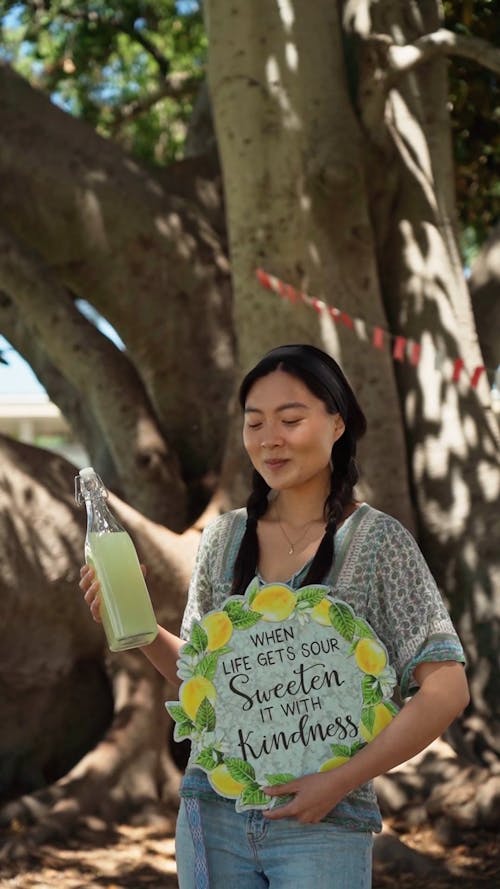 A Woman Holding an Organic Lemonade Juice and a Poster