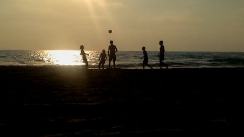 在日落期間在沙灘上打踢球